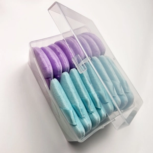 Detail view of purple and blue velvet triangular powder puffs in a transparent storage box