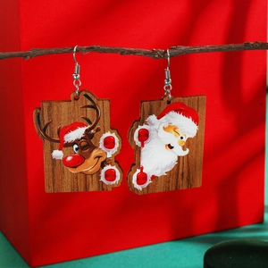 Detail view of Santa and Reindeer wooden earrings hanging on a rustic tree branch