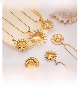 Detail of 18K gold plated stainless steel sun and moon necklaces on white pedestal