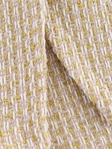Close-up of off-white and light brown tweed fabric with shimmering golden metallic threads