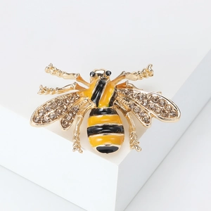 Detailed macro view of yellow enamel bee brooch with sparkling crystal wings on white stand