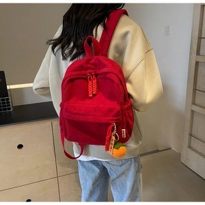 Detail of red corduroy backpack with lucky persimmon pendant and woven zipper head