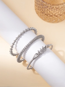 Macro detail of silver-toned titanium steel bangles with textured spiral and wave patterns