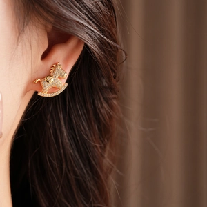 Close-up of sparkling gold rocking horse earrings with crystals on a model