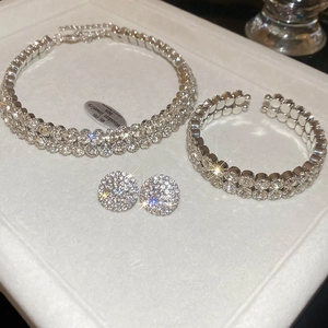 Close-up of sparkling rhinestone necklace bracelet and earrings set on white leather