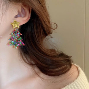 Detail view of festive Christmas tree earrings with gold stars and colorful sequins