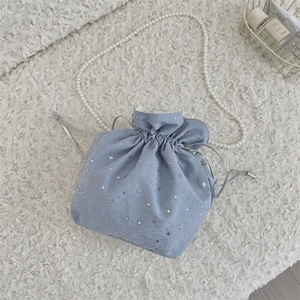 Detail of light blue drawstring bag featuring silver star prints and white pearl chain strap