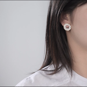 Detailed view of flower earrings with white wavy texture and golden edges on ear