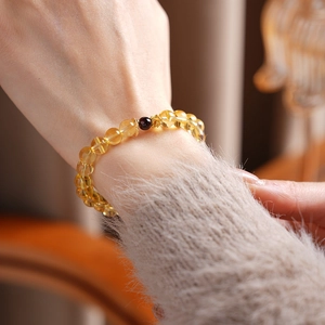 Close-up of natural citrine beads with garnet accent and golden hollow spacers on a wrist
