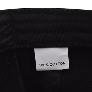 Detailed view of the 100% cotton material tag and twill texture on a black baseball cap