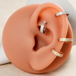 Close-up of gold and silver zircon triple-layered steel rings on a model ear