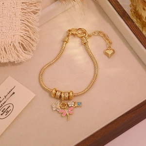 Detailed macro view of 18K gold plated charm bracelet with dragonfly and butterfly motifs