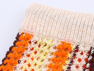 Détail du haut polo au crochet montrant des textures de tricot orange, jaune et marron