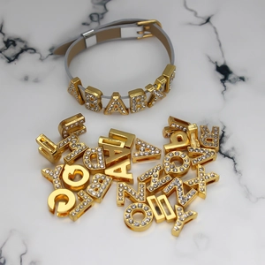 Detailed macro view of 8mm gold rhinestone DIY alphabet slide charms on a bracelet