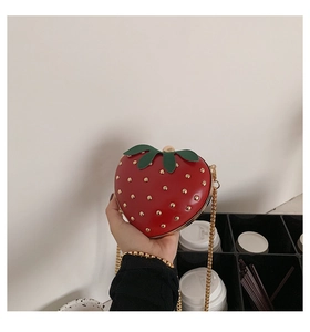 Detailed close-up of a strawberry shaped mini bag with red leather and gold studs