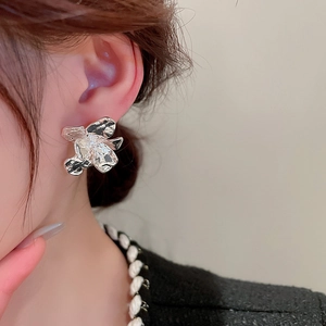 Close-up of silver irregular pleated flower earrings on model with metallic finish