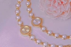 Close-up of pearl luxury watches with gold metal cases on soft pink fabric floral background