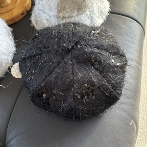 Détails de la texture du béret noir tricoté à paillettes avec fil argenté et fini duveteux