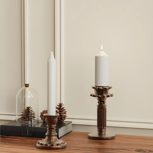 Detailopname van een vintage bronzen kolomkandelaarset met witte stompkaarsen