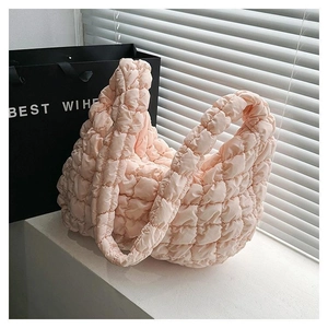 Detail of peach pink quilted cloud tote bag with puffer texture on a bright windowsill