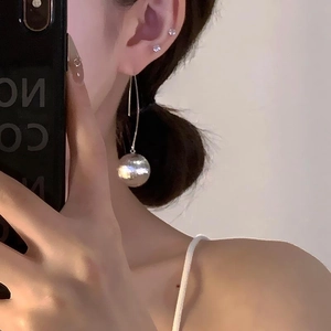 Exaggerated metal ball drop earrings with textured silver spheres on long hooks for women