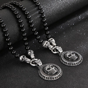 Macro shot of black agate bead necklaces with detailed metal skull and round coin charms