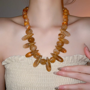 Detail of amber resin beaded necklace with irregular pendants on a model collarbone