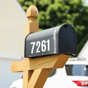 Detail of 4-inch white reflective mailbox number stickers on a black metal post box