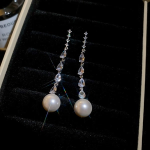 Macro shot of silver pearl drop earrings with sparkling zircon tassels and elegant luster
