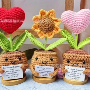 Close-up of three handmade crochet support plants with wood base and cards