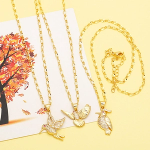 Detailed view of three gold bird pendants with white zircon stones and red gem eyes