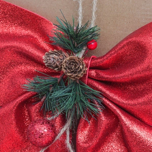 Detail of red glitter Christmas bow with pine cones, pine needles and berries