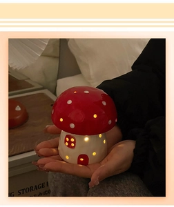 Close-up of ceramic mushroom night light glowing in hands with warm light