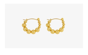 Detailed view of gold beaded hoop earrings with gradient size beads on white background
