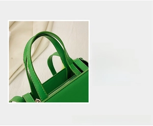 Detail magnification of green synthetic leather tote showing double stitching and metal zipper