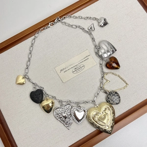 Close-up of mixed material heart pendants and chunky silver chain on linen tray