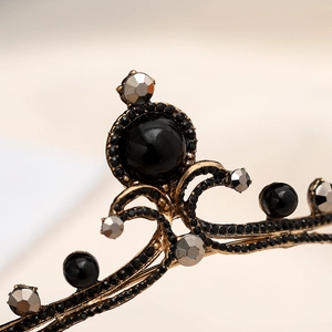 Close-up of Baroque vintage gold crown with black gemstones and gray rhinestones detail
