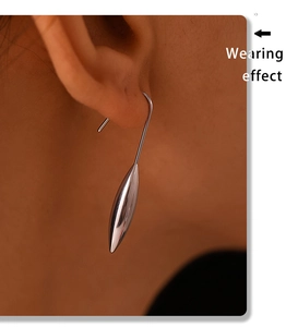 Detail view of silver water-drop earrings showing the streamlined metallic texture on a model