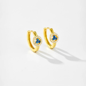 Macro detail of gold hoop earrings with blue and white gemstones on a white base
