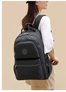Detail view of a black Oxford fabric backpack with multiple compartments on a model