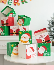 Three festive Christmas gift boxes in red, green, and white on a white table setting
