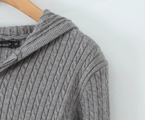 Detailed macro view of the grey cable-knit texture and metallic zipper on this hoodie