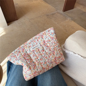 Dettaglio di una trousse trapuntata a fiori con etichetta Simple Wish sulla gamba