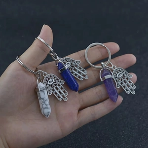 Detailed view of Hamsa Hand crystal keychains held in hand with turquoise and lapis stones