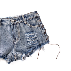 Detail von High-Waist Denim Shorts mit Distressed-Rissen und seitlicher Schnürung