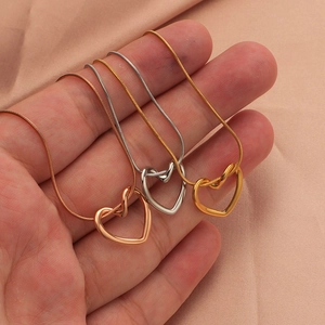 Close-up of gold, silver, and rose gold hollow heart pendants on delicate snake chains