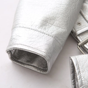 Close-up of silver metallic faux leather jacket featuring sleeve seams and buckle detail