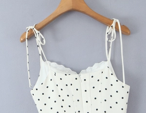 Detail of white polka dot top featuring bow tie straps and delicate lace trim on neckline