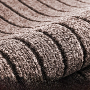Macro shot of deep vertical grooves on a brown anti-slip door mat for dust removal