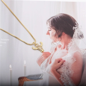 Close-up of golden ox head pendant with zircon stones and box chain on a bride